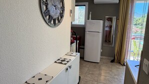A kitchen with a clock, a white cabinet, a refrigerator, and a window with curtains. - Studio 2OO M Centre Saint Florent -in quiet building. (Saint-Florent)