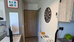 Et lille køkken med spiseplads, et ur på væggen og en støvsuger.