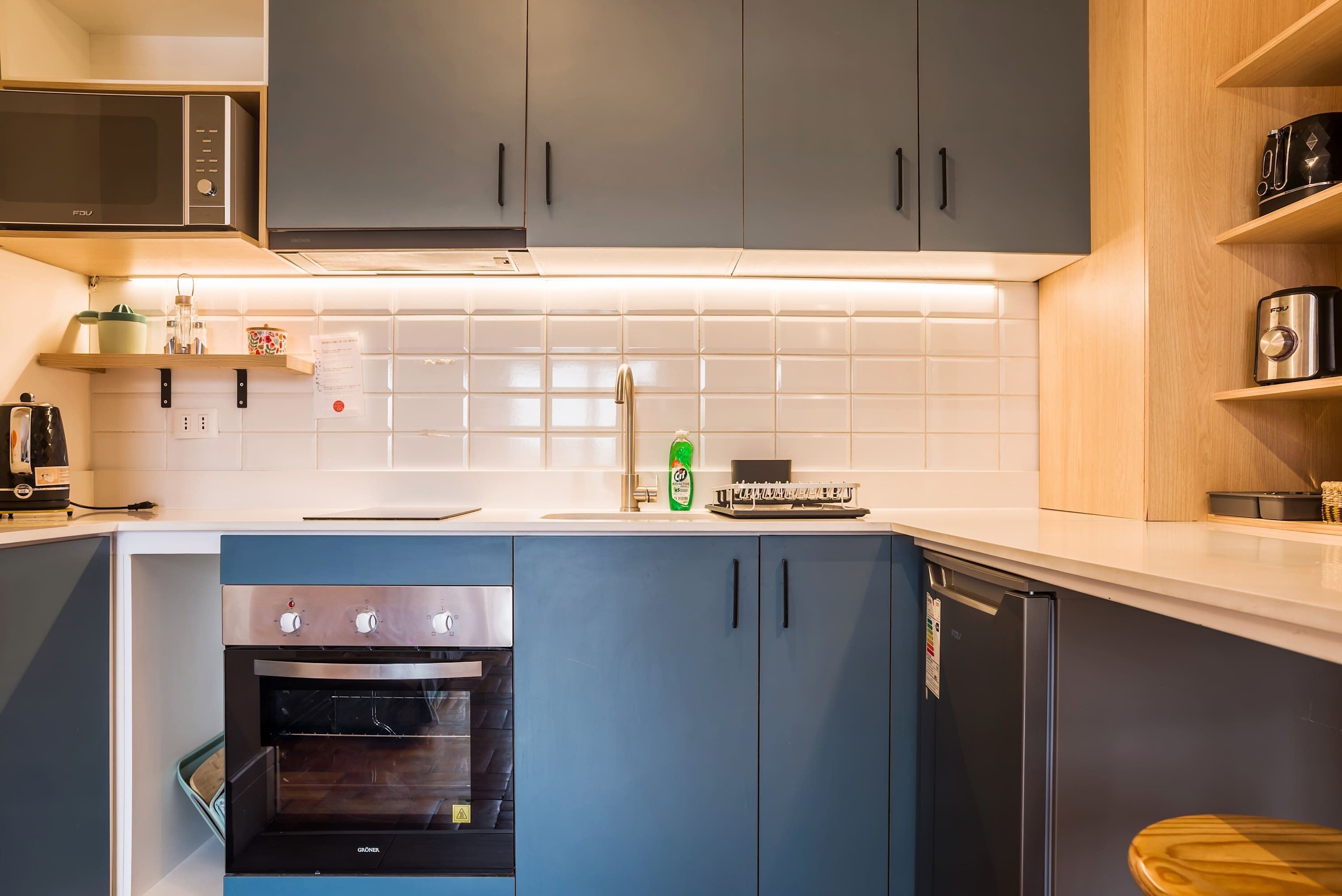 A compact kitchen with a microwave, oven, and dishwasher, and wooden cabinets.
