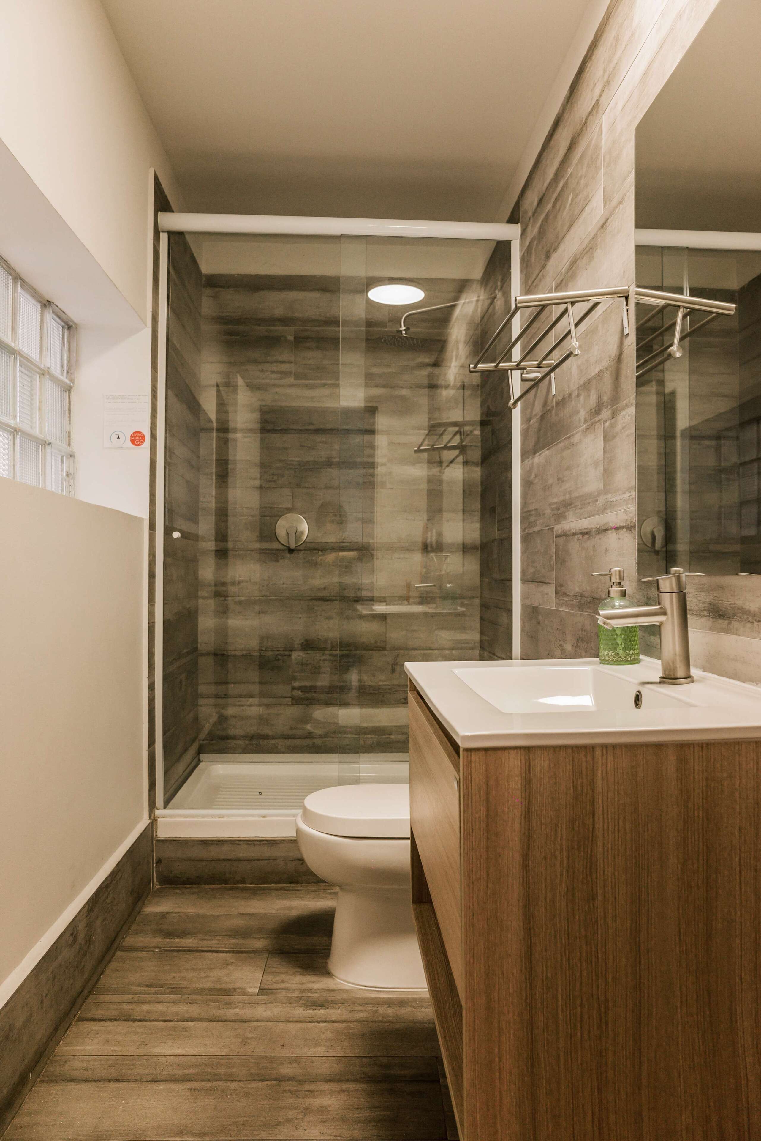 Et moderne badeværelse med et glasafskærmet brusebad, et træbordplade og et toilet.