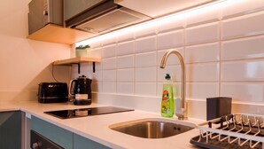 A modern kitchen with a sink, a coffee maker, a kettle, and a dish rack. - Bright & Modern Studio Prime Providencia Location (Providencia)