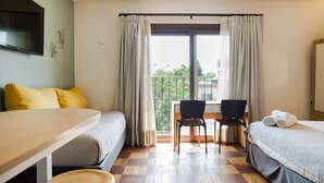 A hotel room with two beds, a desk, and a chair. There is a balcony with curtains and a view of the outside. - Bright & Modern Studio Prime Providencia Location (Providencia)