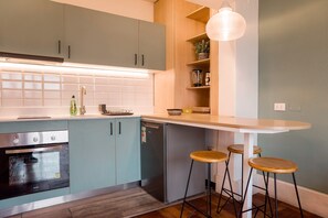 A kitchen with a built-in oven, a refrigerator, a sink, and a bar area with stools. - Bright & Modern studio Stay in Emilio Vaisse (Providencia)