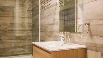 A modern bathroom with a wooden vanity, a glass shower enclosure, and a large mirror.