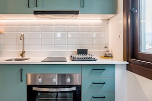 A kitchen with teal cabinets, a stainless steel oven, and a white countertop.