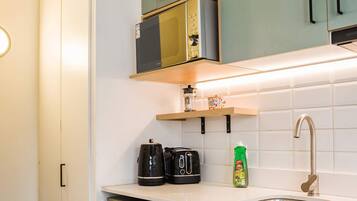 A compact kitchen with a refrigerator, a coffee maker, a toaster, and a sink.