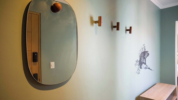 Une salle de bain avec un miroir rond, un meuble en bois et un porte-serviettes fixé au mur.