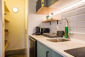 A compact kitchen with a sink, a kettle, a dish rack, and a bottle of dish soap. - Style and Comfort in Providencia Ideal for 2 (Providencia)