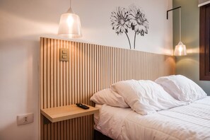 Ein Hotelzimmer mit einem hölzernen Lattenrost am Kopfteil, einem Nachttisch mit Fernbedienung und einer Wandleuchte.
