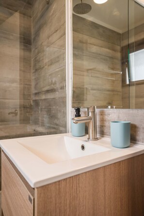 Ein Badezimmer mit einem weißen Waschbecken, einem Spiegel und einer Dusche mit Glastür.