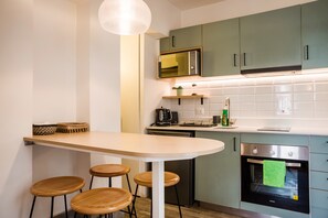 Una cocina moderna con una isla central, taburetes de bar, microondas, hervidor y horno empotrado.