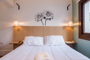 A hotel room with a bed, bedside tables, a wall-mounted lamp, and a window. - Style and Comfort in Providencia Ideal for 2 (Providencia)