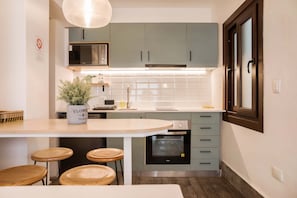 A compact kitchen with a microwave, oven, and a potted plant on the counter.