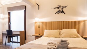 Een hotelkamer met een bed, bureau, stoel en een kunstwerk aan de muur.