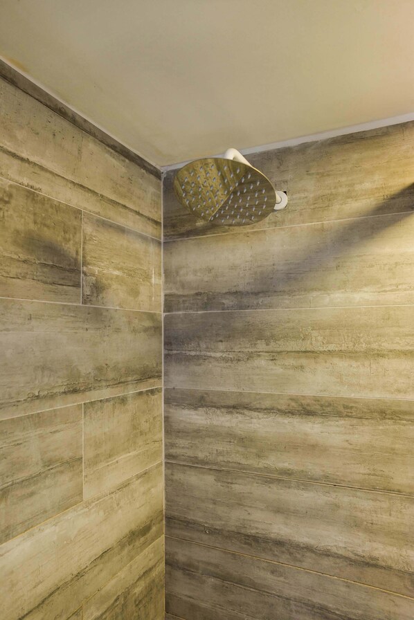 A shower with a unique, textured wall design and a modern showerhead.