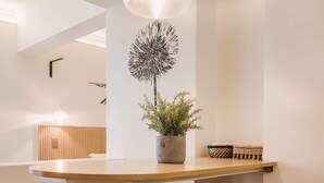 Een moderne keuken met een houten tafel, vier krukken, een hanglamp en een potplant.