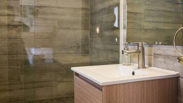 A modern bathroom with a glass shower enclosure, a wooden vanity, and a large mirror.