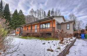 A two-story cabin with a covered porch, surrounded by snow and trees. - Chalet Béatitude (Val-des-Bois)
