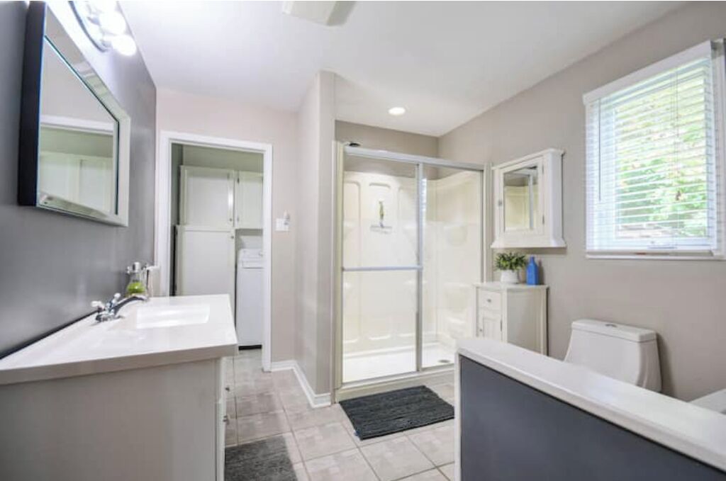 Une salle de bain moderne avec un grand miroir, un lavabo, des toilettes et un espace douche.