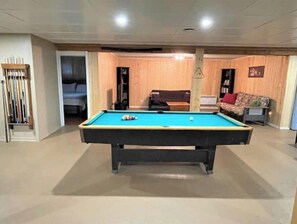 A pool table in a room with wooden walls and a sofa. - Chalet Béatitude (Val-des-Bois)
