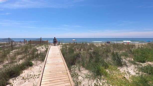 A wooden boardwalk leading to a beach with sparse vegetation and a clear blue sky. - Island Suites - Beachfront, boutique hotel, walk to lighthouse, dining & more (St George Island)