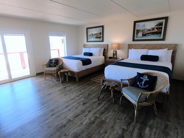 Une chambre d’hôtel avec deux lits, un plancher en bois et une vue sur l’extérieur grâce à une grande fenêtre.