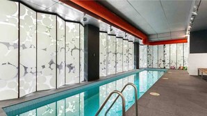 Ein Schwimmbecken mit modernem Design, darunter eine Glaswand mit Wabenmuster und eine Metallleiter.