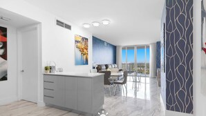 Eine moderne Küche mit einer zentralen Kochinsel, einem Essbereich mit Aussicht und einer Wand mit Musterdesign.