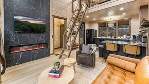 Ein modernes Interieur mit Kamin, einer Treppe, einer Küchenzeile und einer Sitzecke.