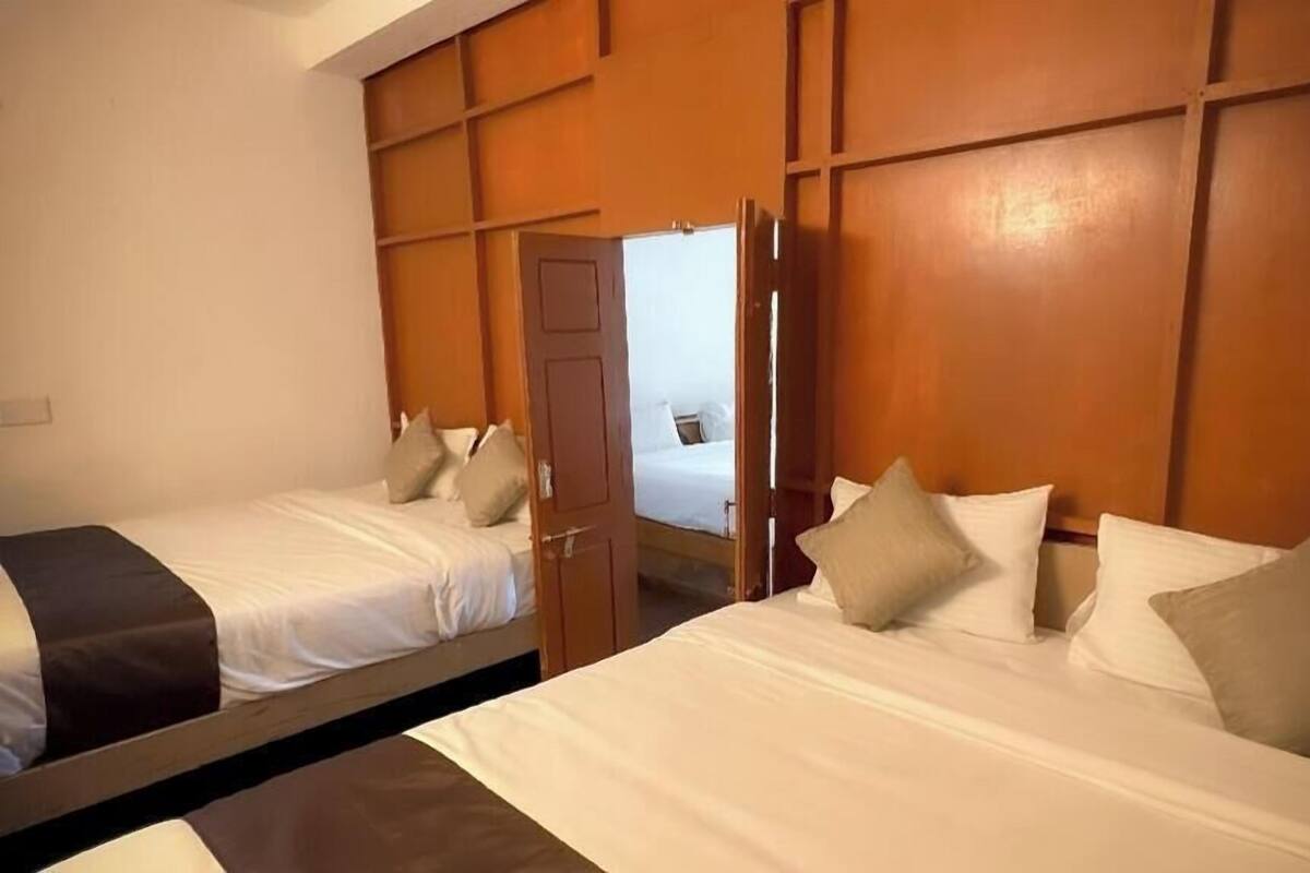 A hotel room with two beds, wooden headboards, and a mirror reflecting the room.