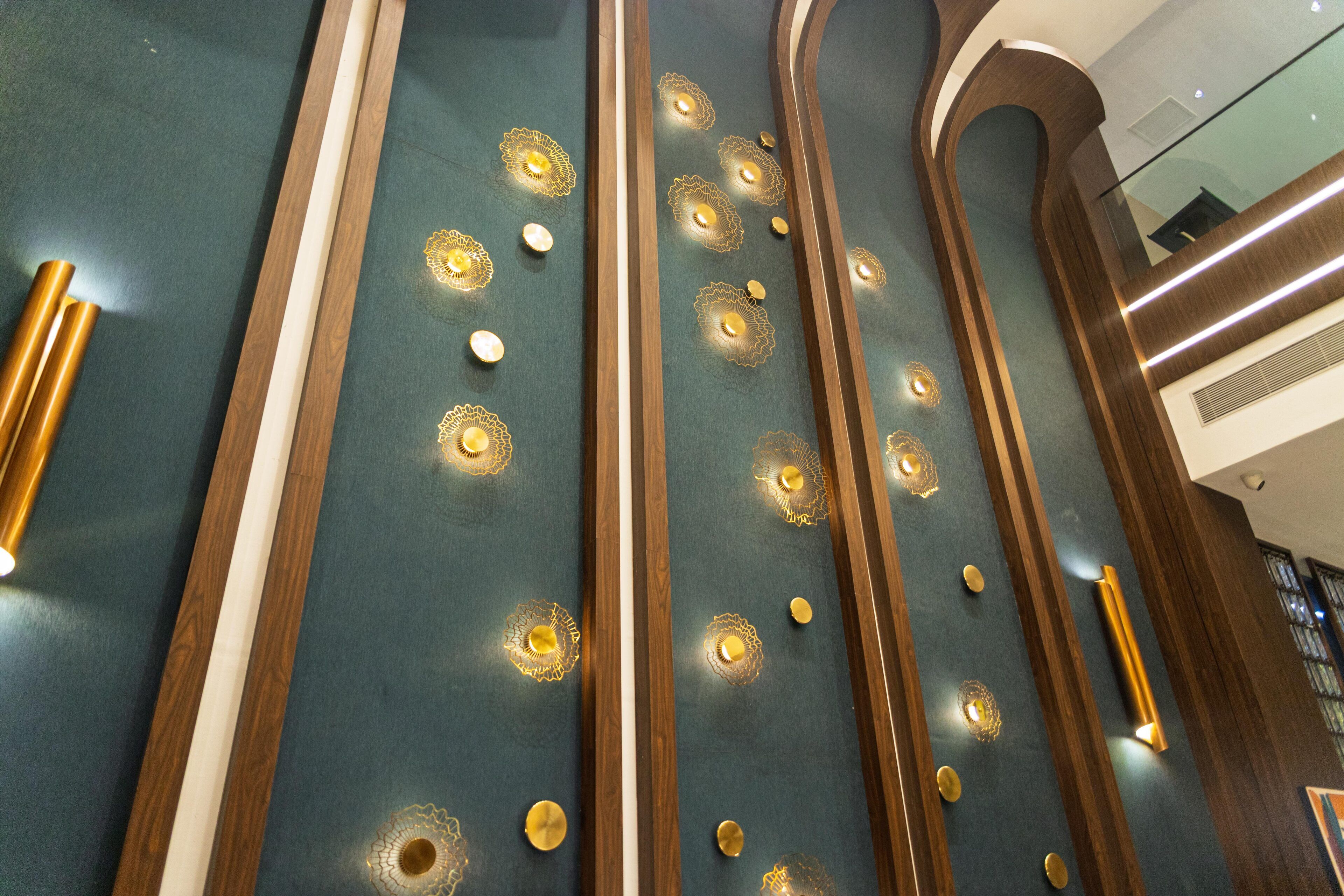 A modern interior with a dark green wall featuring decorative golden patterns and vertical wooden accents.