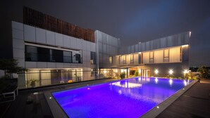 A modern building with a large outdoor pool, featuring a wooden deck and a glass facade. - ESP Hotel (Accra)