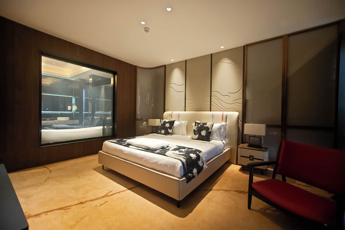 Una camera da letto moderna con un letto grande, una sedia rossa e vista sul bagno.