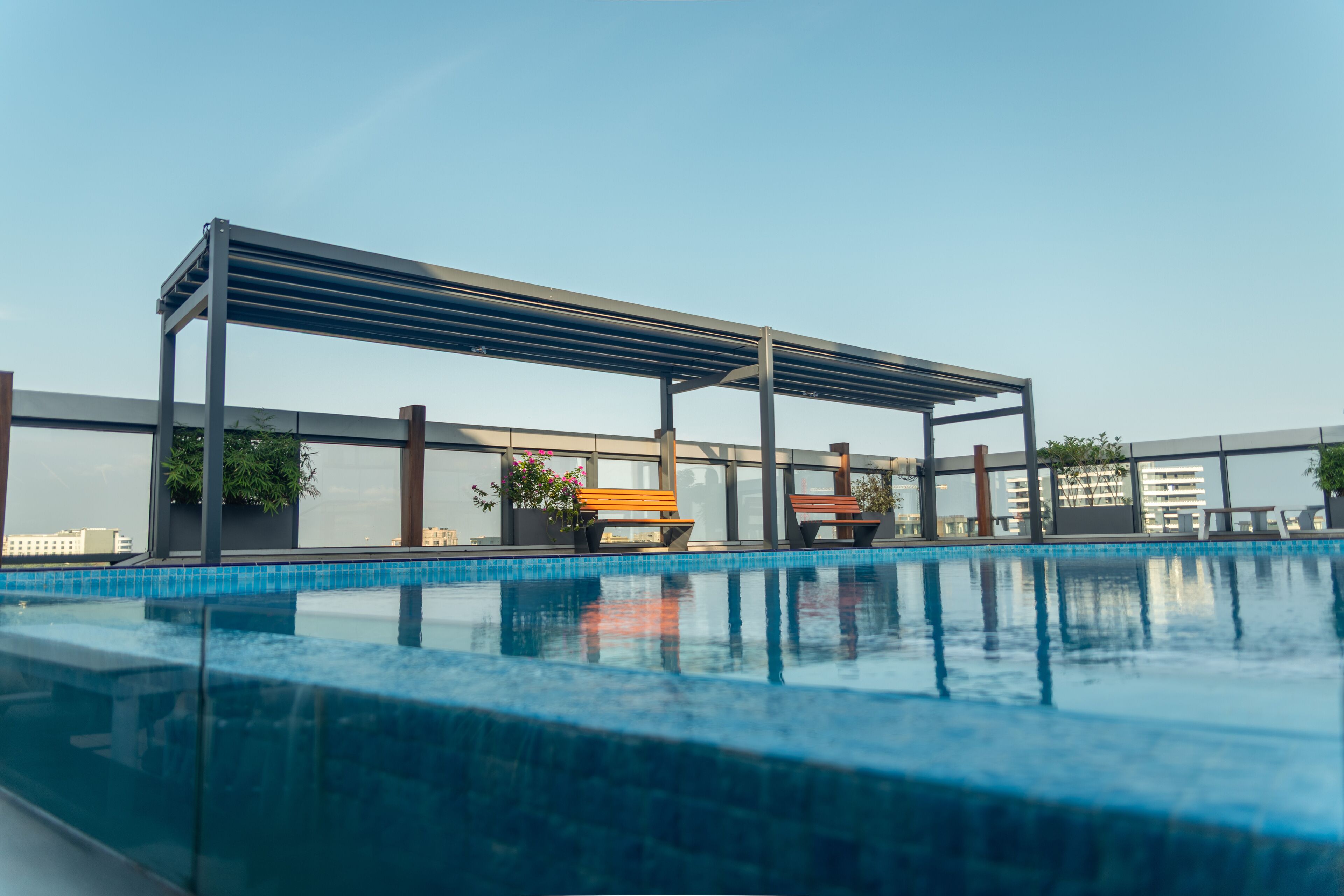 Ein Dachpool mit Pergola, Sitzgelegenheiten und Topfpflanzen.