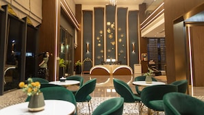 A hotel lobby with a reception desk, green upholstered chairs, and a chandelier. - ESP Hotel (Accra)