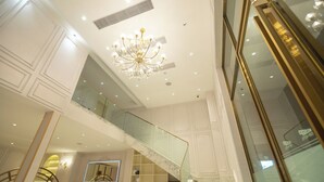 A luxurious interior with a grand staircase, a chandelier, and a modern bathroom with a vanity and mirror. - ESP Hotel (Accra)