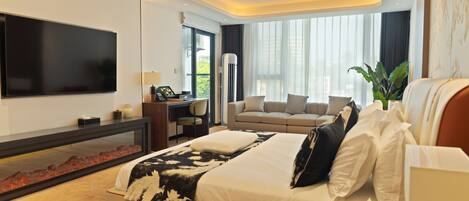 A modern hotel room with a large bed, a desk, a sofa, and a TV.