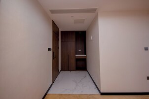 A narrow hallway with a wooden door and a small shelf.