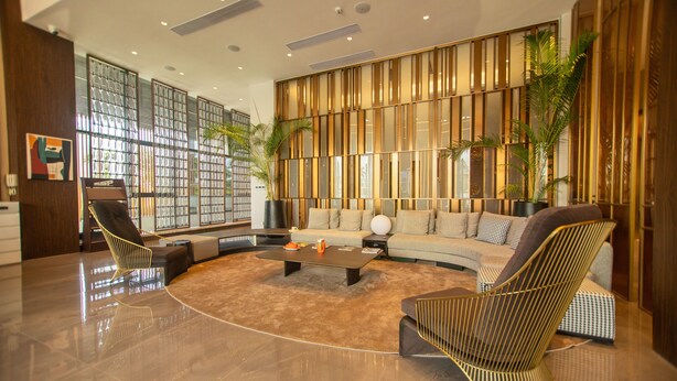 A spacious living area with a modern design, featuring a large sofa, two armchairs, a coffee table, and a bookshelf. - ESP Hotel (Accra)