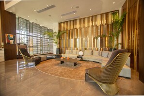 A spacious living area with a modern design, featuring a large sofa, two armchairs, a coffee table, and a bookshelf.