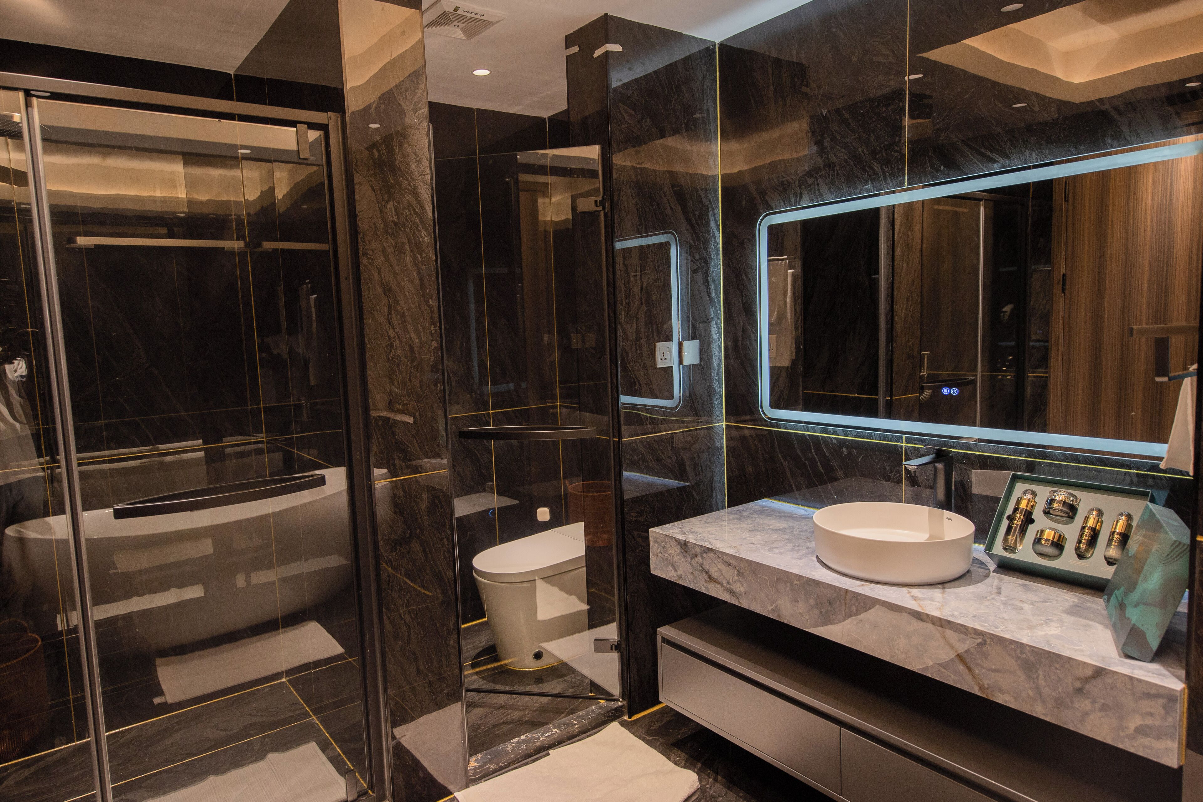 Une salle de bain moderne avec une douche à parois de verre, un meuble-lavabo en marbre et un grand miroir.