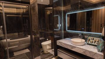 Une salle de bain moderne avec une douche à parois de verre, un meuble-lavabo en marbre et un grand miroir.