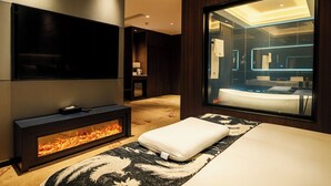 A modern bedroom with a fireplace, a large mirror, and a view of the bathroom. - ESP Hotel (Accra)