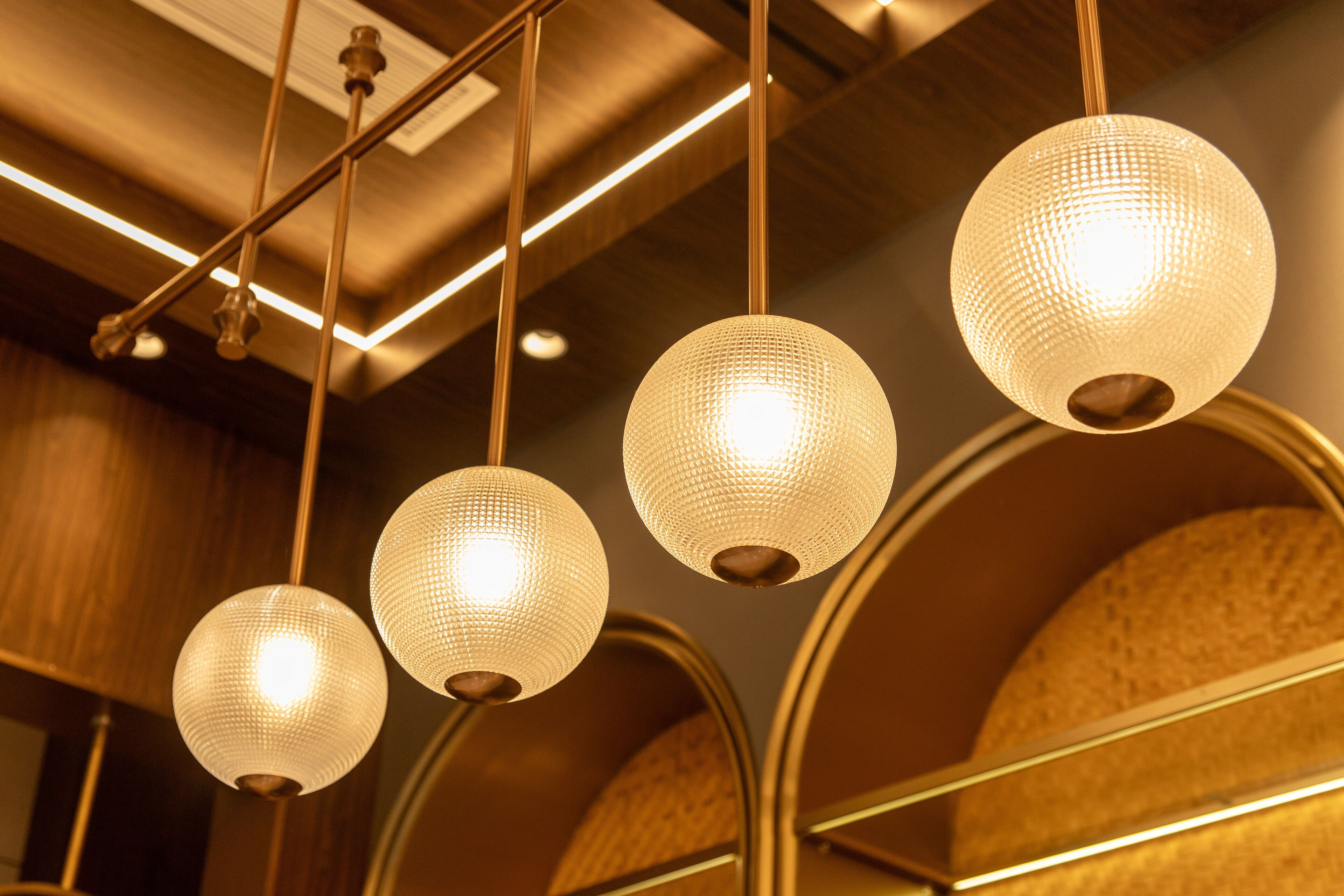 A ceiling with multiple spherical light fixtures and a wooden ceiling design.