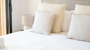 A neatly made bed with pillows and a rolled towel, a bedside lamp, and a window with a view. - Villa Benedettu (Lecci)