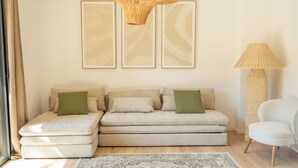 A modern living room with a sectional sofa, a green ottoman, a large woven floor lamp, and abstract wall art. - Villa Benedettu (Lecci)