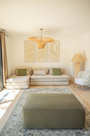 A modern living room with a sectional sofa, a green ottoman, a large woven floor lamp, and abstract wall art. - Villa Benedettu (Lecci)