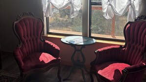 A room with two red upholstered chairs, a small round table, and a window with sheer white curtains. - Secluded and cozy cabin in the country. Dark skies for star gazing. (Rocksprings)