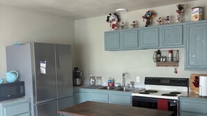 A compact kitchen with a central island, stainless steel appliances, and light blue cabinetry. - Secluded and cozy cabin in the country. Dark skies for star gazing. (Rocksprings)
