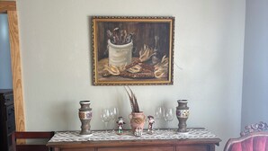 A wooden cabinet with a white tablecloth, a painting of a still life, and a patterned rug. - Secluded and cozy cabin in the country. Dark skies for star gazing. (Rocksprings)